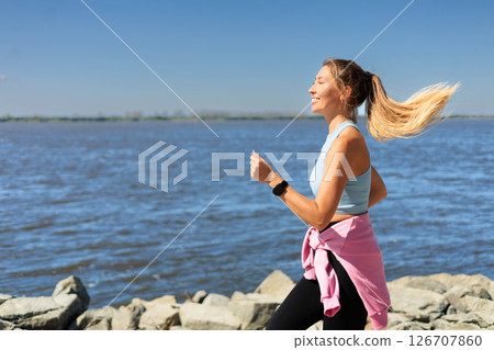 Sport woman morning running jogging on city river embankment side view 126707860