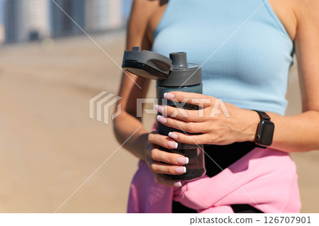 Smiling young blonde woman jogger runner drink water from bottle at river embankment closeup Smiling young blonde woman jogger runner drink water from bottle at river embankment closeup 126707901