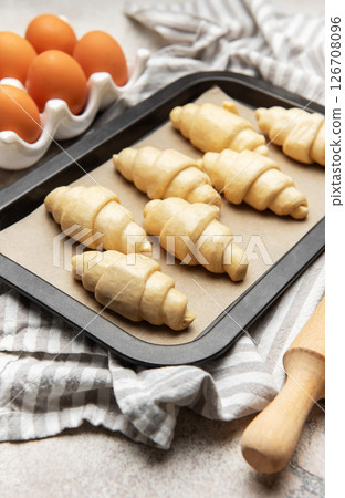 Freshly made croissants resting on baking sheet await oven's warm embrace 126708096
