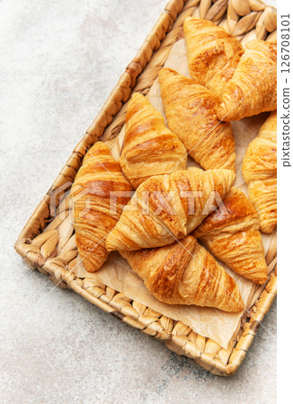 Freshly baked croissants resting on a wicker tray, a delightful breakfast scene 126708101