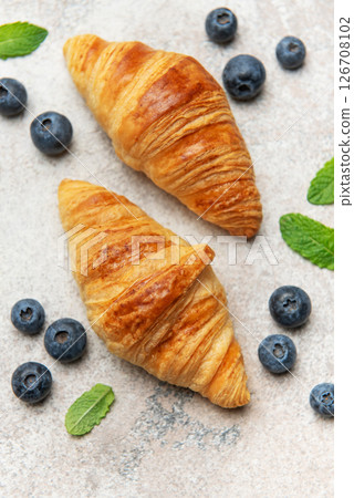 Delicious french croissants with fresh blueberries and mint on a textured background Delicious french croissants with fresh blueberries and mint on a textured background 126708102