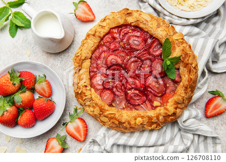 Delicious homemade strawberry galette decorated with almond petals and fresh mint 126708110