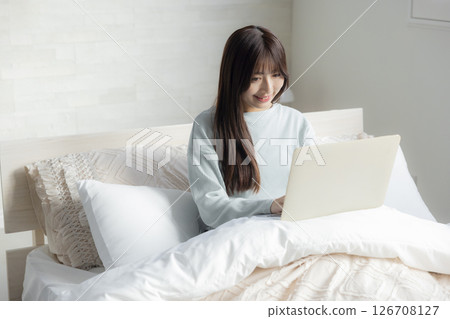 一個女人在床上拿電腦 126708127