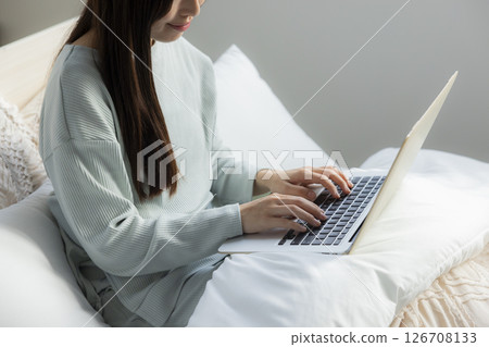 一個女人在床上拿電腦 一個女人在床上拿電腦 126708133