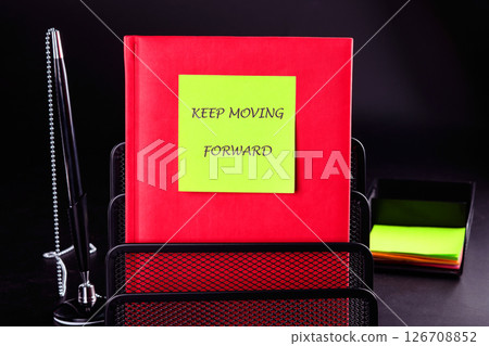 Business, motivation and keep moving forward concept. KEEP MOVING FORWARD written on a green sticker on a red business book on a black background 126708852