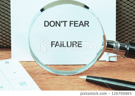 Concept text DO NOT FEAR FAILURE focused on the notebook through a magnifying glass Concept text DO NOT FEAR FAILURE focused on the notebook through a magnifying glass 126708865
