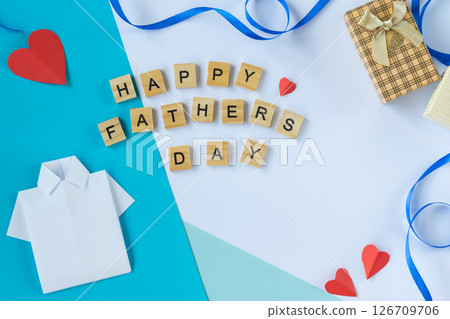 Flat lay photo with Fathers Day paper shirt tie red blue hearts wooden letter tiles gift box greeting card layout for dad celebration concept white and blue festive background Flat lay photo with Fathers Day paper shirt tie red blue hearts wooden letter tiles gift box greeting card layout for dad celebration concept white and blue festive background 126709706