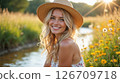 A young woman in a sunlit meadow near the river 126709718