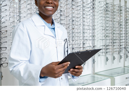 Female african american optician in a lab coat looking contented and positive 126710040