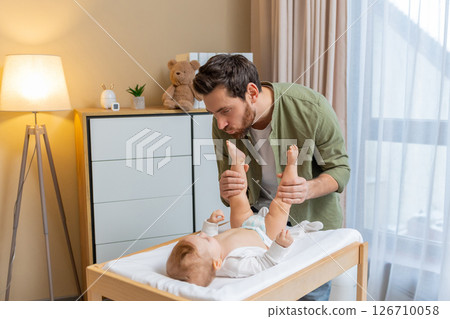 Dad playing with his baby boy while a child lying on a changing table Dad playing with his baby boy while a child lying on a changing table 126710058