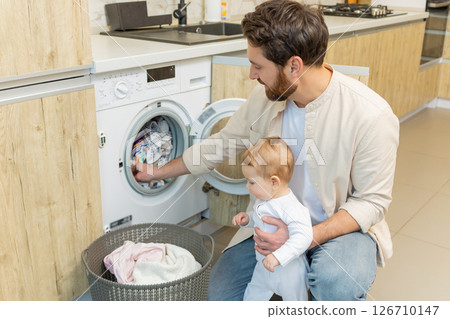 Young man and his little son sorting clothes before putting into washing machine Young man and his little son sorting clothes before putting into washing machine 126710147