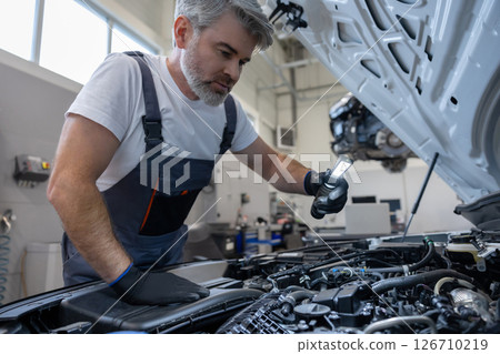 Mechanic inspecting engine with flashlight Mechanic inspecting engine with flashlight 126710219