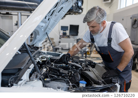 Mechanic checking engine oil in workshop Mechanic checking engine oil in workshop 126710220