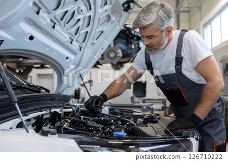 Mechanic checking engine oil in workshop 126710222
