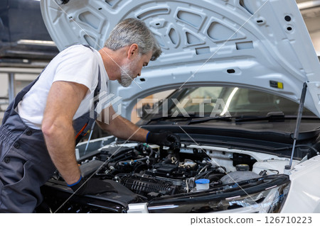 Mechanic checking oil level in engine 126710223