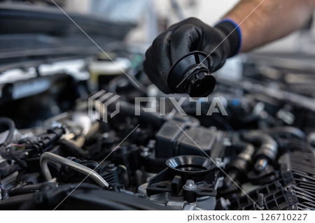Mechanic checking oil level in engine 126710227