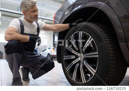 Mechanic examining wheel in workshop 126710235