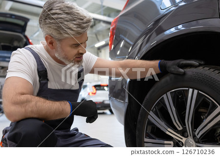 Mechanic inspecting wheel 126710236