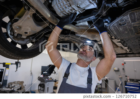 Mechanic with headlamp under vehicle 126710752