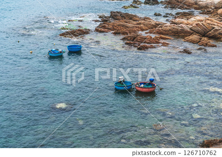 Vietnamese round basket boats floating in the sea next to the rocks 126710762