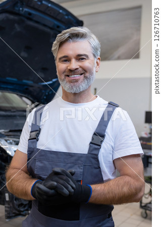 Mechanic holding gloves in workshop Mechanic holding gloves in workshop 126710763