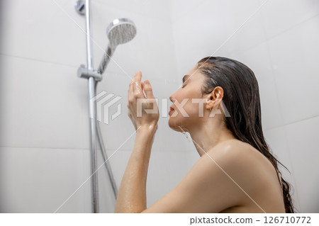 Woman showering in bathroom washing hair enjoying healthy skincare and hygiene time 126710772