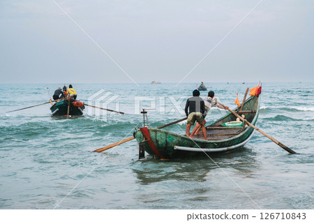 Vietnamese fishermen men on traditional boats in sea at a fishing village in Vietnam Vietnamese fishermen men on traditional boats in sea at a fishing village in Vietnam 126710843