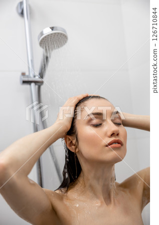 Woman showering with water in bathroom washing body relaxing at home 126710844