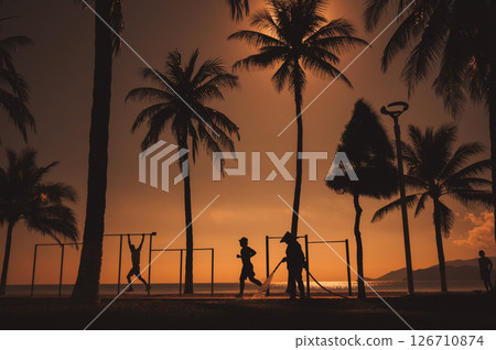 silhouettes of people on the embankment with palm trees by the sea at sunrise on summer morning silhouettes of people on the embankment with palm trees by the sea at sunrise on summer morning 126710874