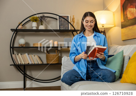 Smiling relaxed woman holding tab relaxing on sofa at home using digital tablet sitting on couch 126710928