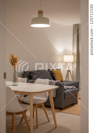 View of dining area and living room with white table, blue vase centerpiece, gray sofa and floor lamp View of dining area and living room with white table, blue vase centerpiece, gray sofa and floor lamp 126711580