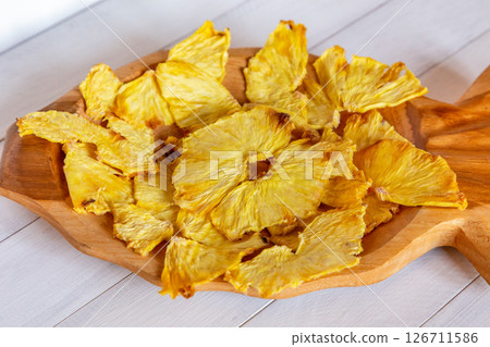 Close up of dried pineapple pieces in a wooden pineapple shaped bowl showing texture and natural details Close up of dried pineapple pieces in a wooden pineapple shaped bowl showing texture and natural details 126711586
