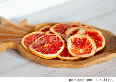 Close up of dried grapefruit slices in a wooden pineapple shaped bowl emphasizing texture and detail Close up of dried grapefruit slices in a wooden pineapple shaped bowl emphasizing texture and detail 126711599
