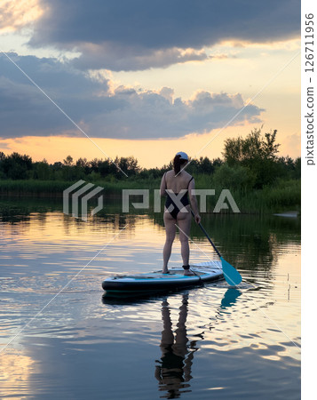Paddleboarding at Sunset on a Tranquil Lake 126711956