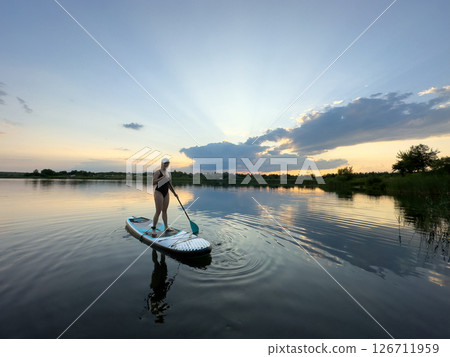 Paddleboarding at Sunset on a Tranquil Lake 126711959