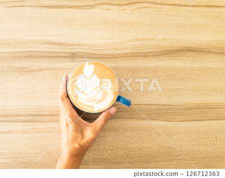 Hand holding cup of latte art coffee homemade on wooden background. copy space for your text Hand holding cup of latte art coffee homemade on wooden background. copy space for your text 126712363