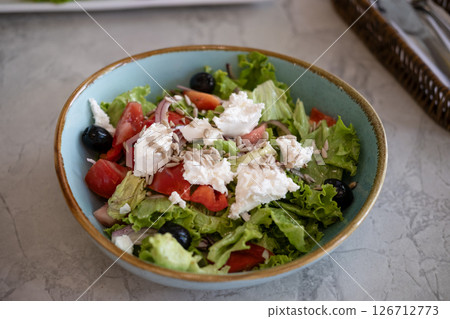 Greek salad in a plate on a table in a restaurant Greek salad in a plate on a table in a restaurant 126712773
