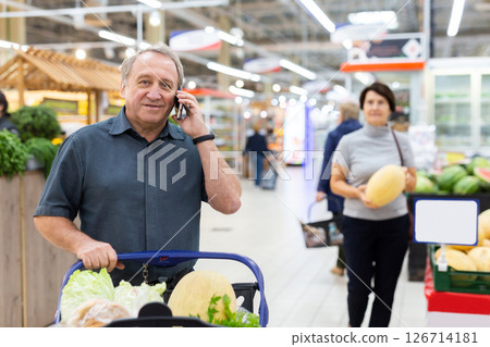 Elderly man talking on mobile phone in supermarket 126714181