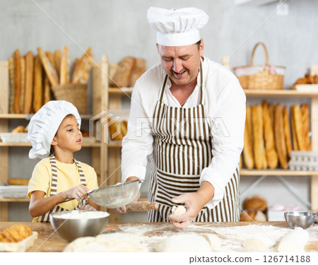 Bakers dad teaches daughter niece to work with dough, using rolling pin Bakers dad teaches daughter niece to work with dough, using rolling pin 126714188