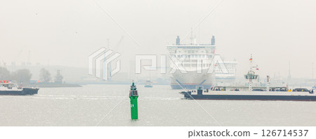 Warnemunde , Germany - March 31, 2024.  Big modern Skane  Siena line ferry ship navigate from Rostock harbor bay foggy spring morning misty weather. Maritime traffic passenger cargo vessel Baltic sea 126714537