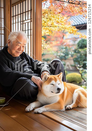 An elderly man and his dog snuggle together on a veranda on an autumn day 126715254
