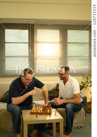 Father and adult son enjoying a game of chess in cozy living room. Fathers day concept. 126715314