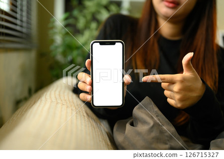 Woman pointing at smartphone with blank display ready for digital content showcase 126715327