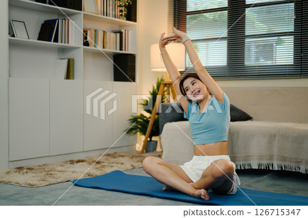 Attractive young woman stretching on mat during a home workout 126715347