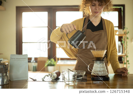 Calm young woman making a fresh cup of coffee using pour-over method 126715348