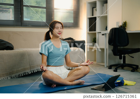 Asian woman practicing mindfulness and breathing exercises in a living room Asian woman practicing mindfulness and breathing exercises in a living room 126715361