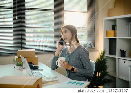 Young business owner communicating with client and drinking coffee at modern workplace 126715397