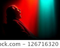 Dramatic Silhouette of a Person Bathed in Red and Green Light 126716320