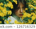 Woman Amidst a Field of Vibrant Yellow Flowers with a Dreamy and Serene Expression 126716329