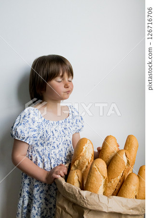 Caucasian young girl enjoying fresh baguette bread in a basket 126716706